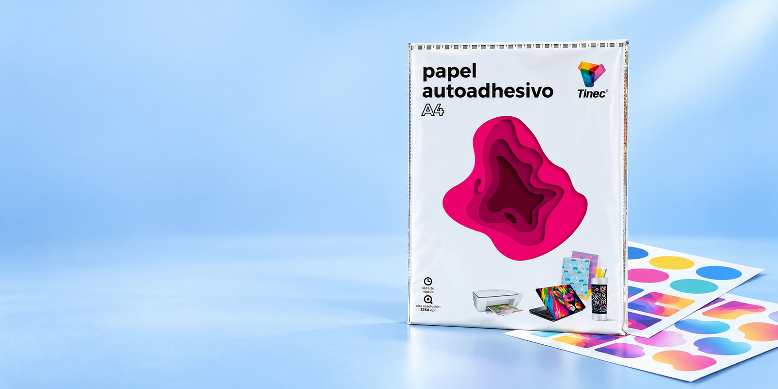 Papel fotográfico adhesivo Tinec de 135 gramos en una composición de papelería sobre fondo azul